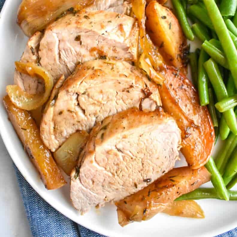 Pork Tenderloin with Apples and Onions  on a white plate with green beans.