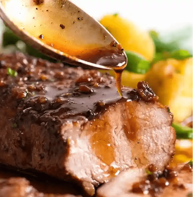 Close up of spoon drizzling Honey Garlic Sauce  over slices of Pork Tenderloin.