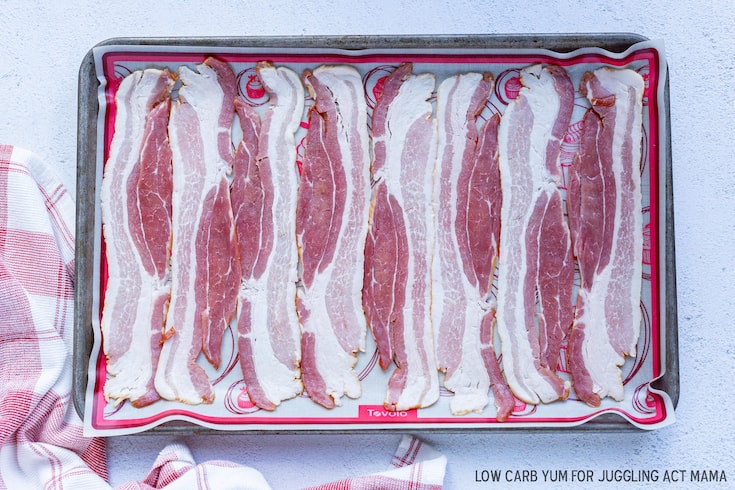 Uncooked bacon on a sheet pan.
