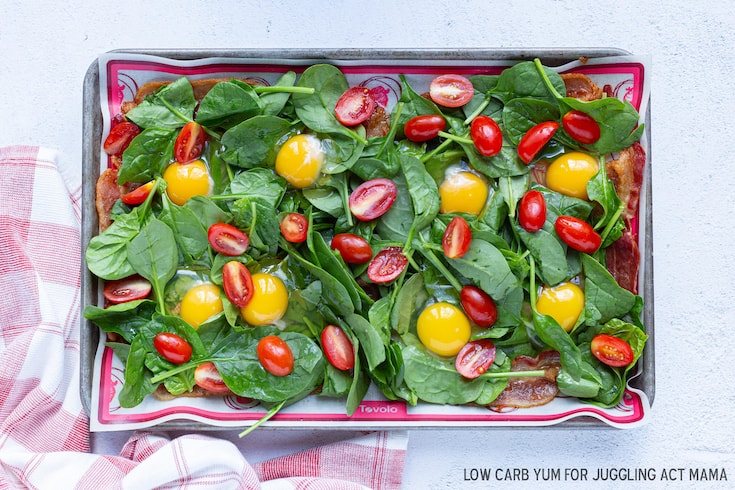 Tomatoes and spinach on a sheet pan with bacon.