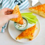 Hand holding a Buffalo Chicken Puff Pastry Pocket dipping into ranch dressing.
