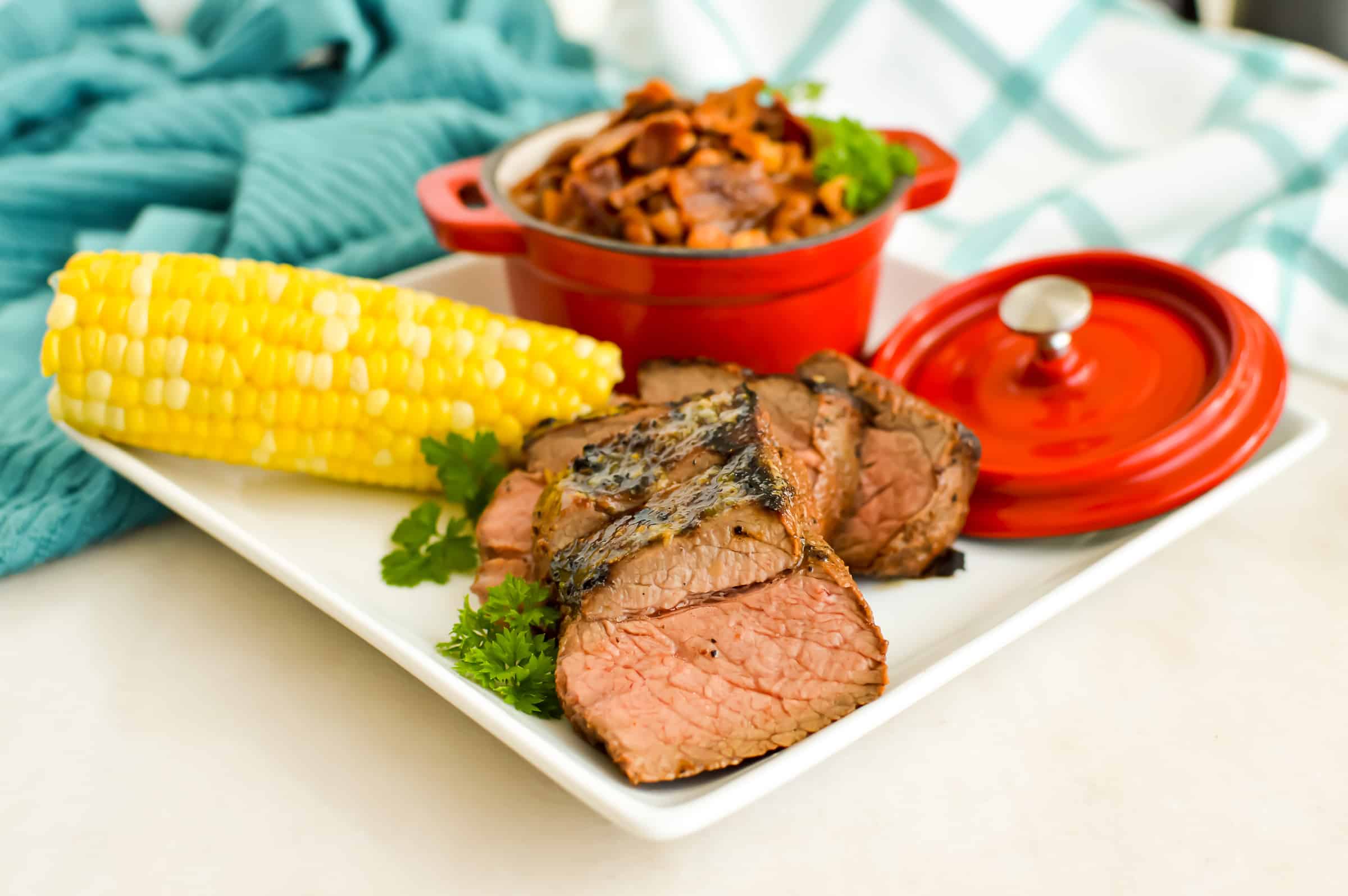Large plate with grilled steak, corn on the cob and cowboy beans.