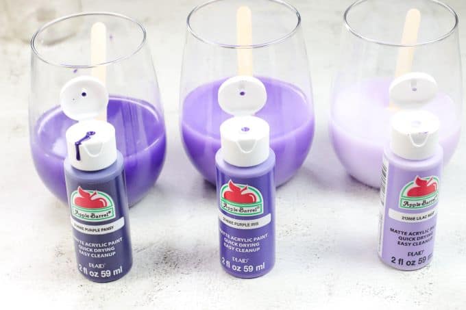 bottles of purple acrylic paint in front of glasses