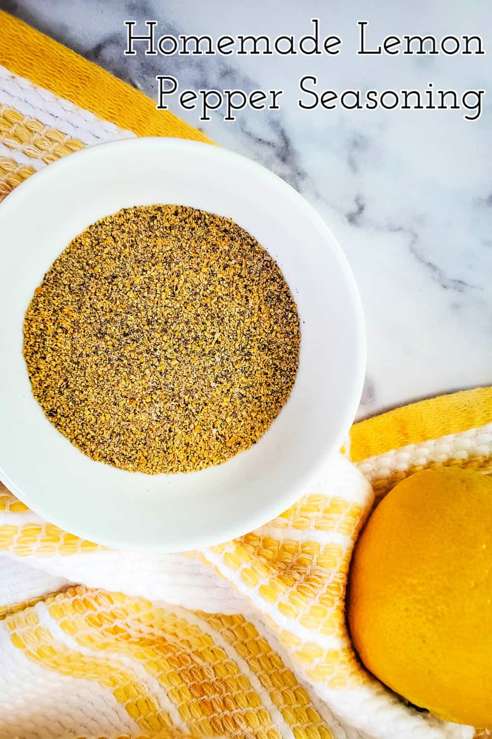 Top down view of homemade lemon pepper seasoning in a small bowl with a yellow and white hand towel.