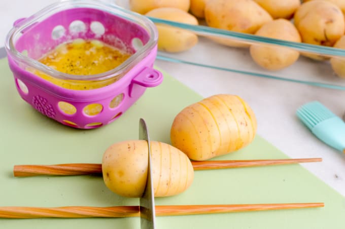 Small potato between two chop sticks with slices partially made.