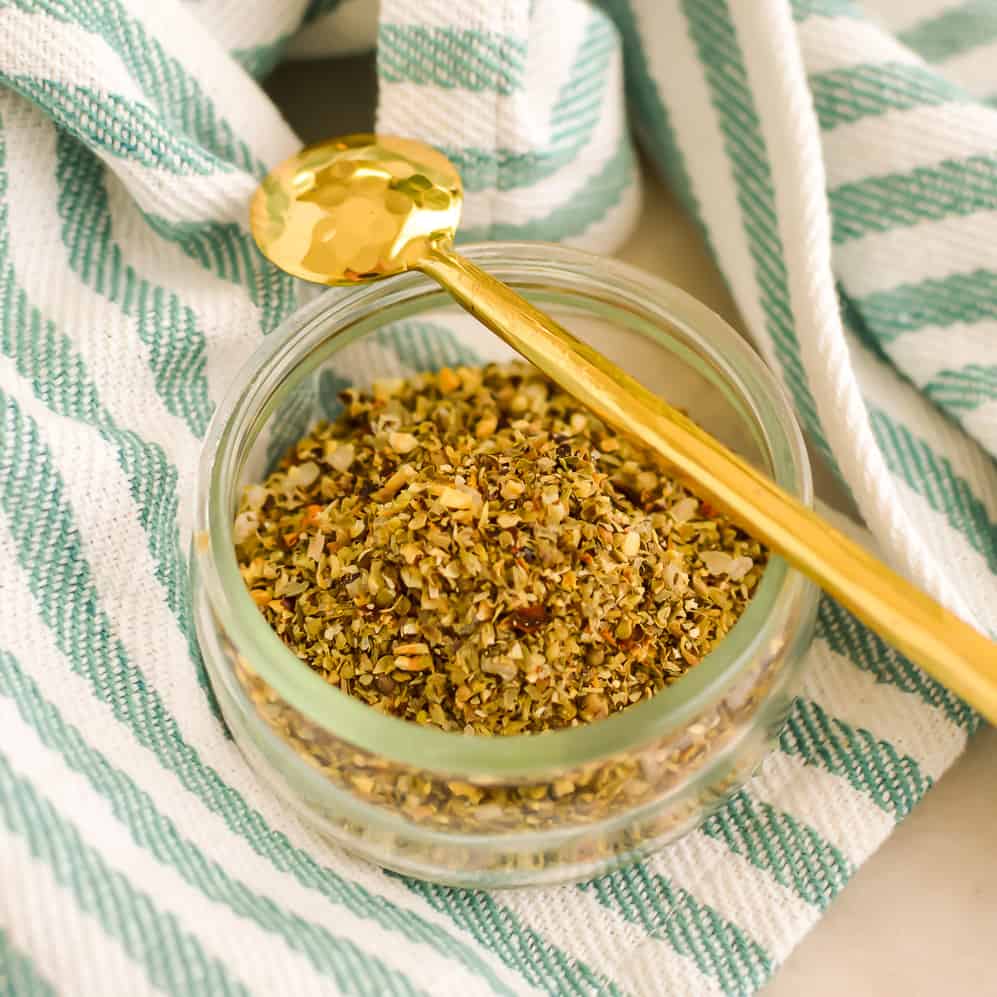 Mediterranean Spice Mix in a jar with a gold spoon resting on top.