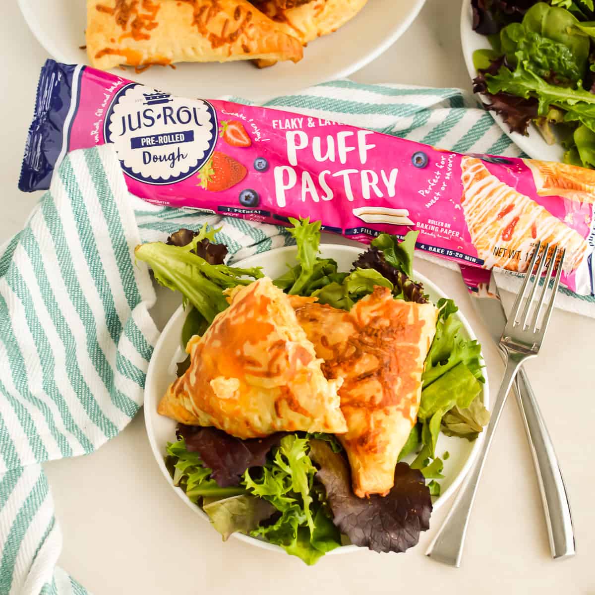 Buffalo Chicken Puff Pastry on a plate with greens next to a package of puff pastry.