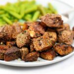 Close up of Steak Bites and Potatoes on a white plate with green beans.