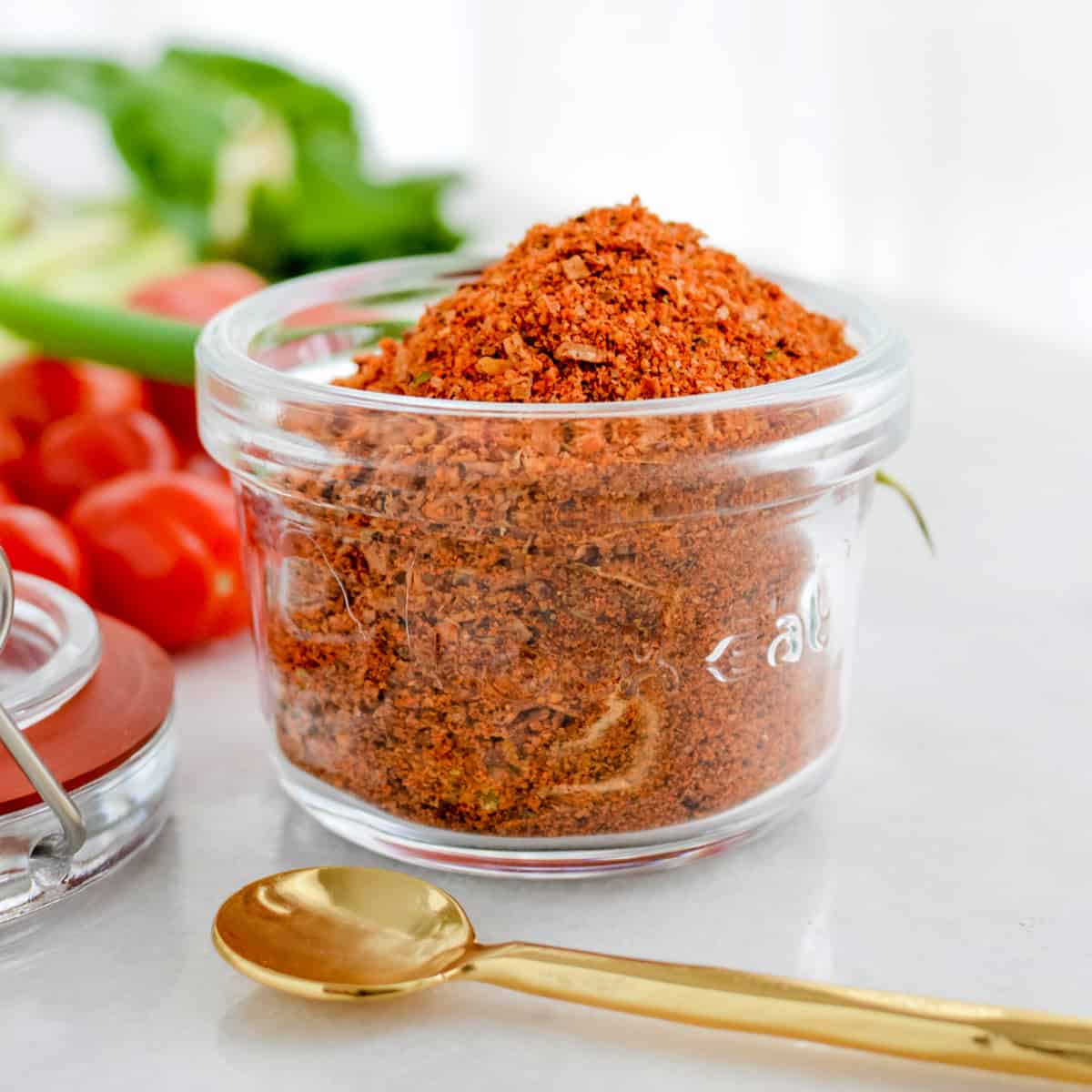 Small jar of Taco Seasoning on a counter with a gold spoon.