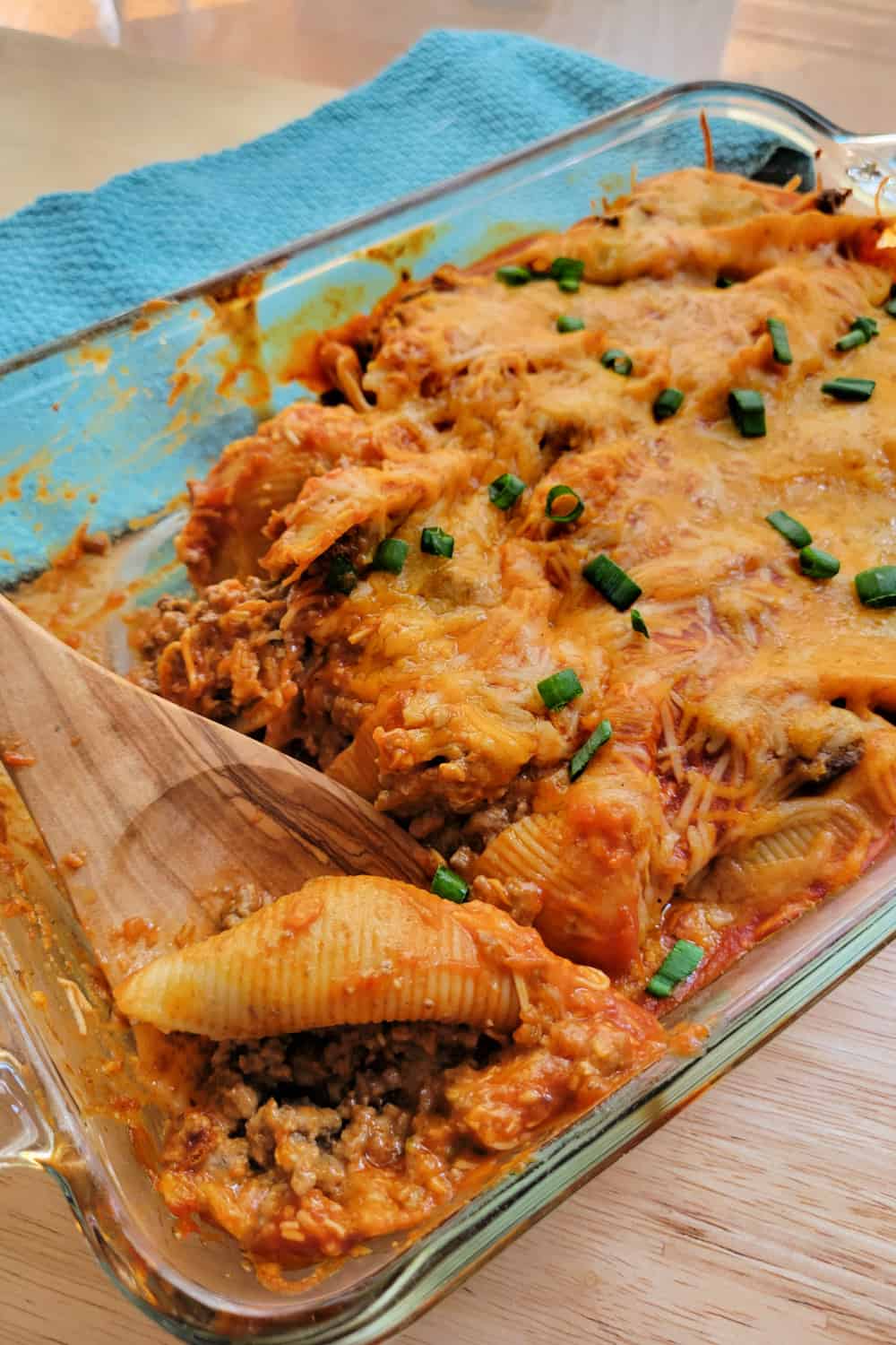 Taco Stuffed Shells in a casserole dish with a wooden spoon.
