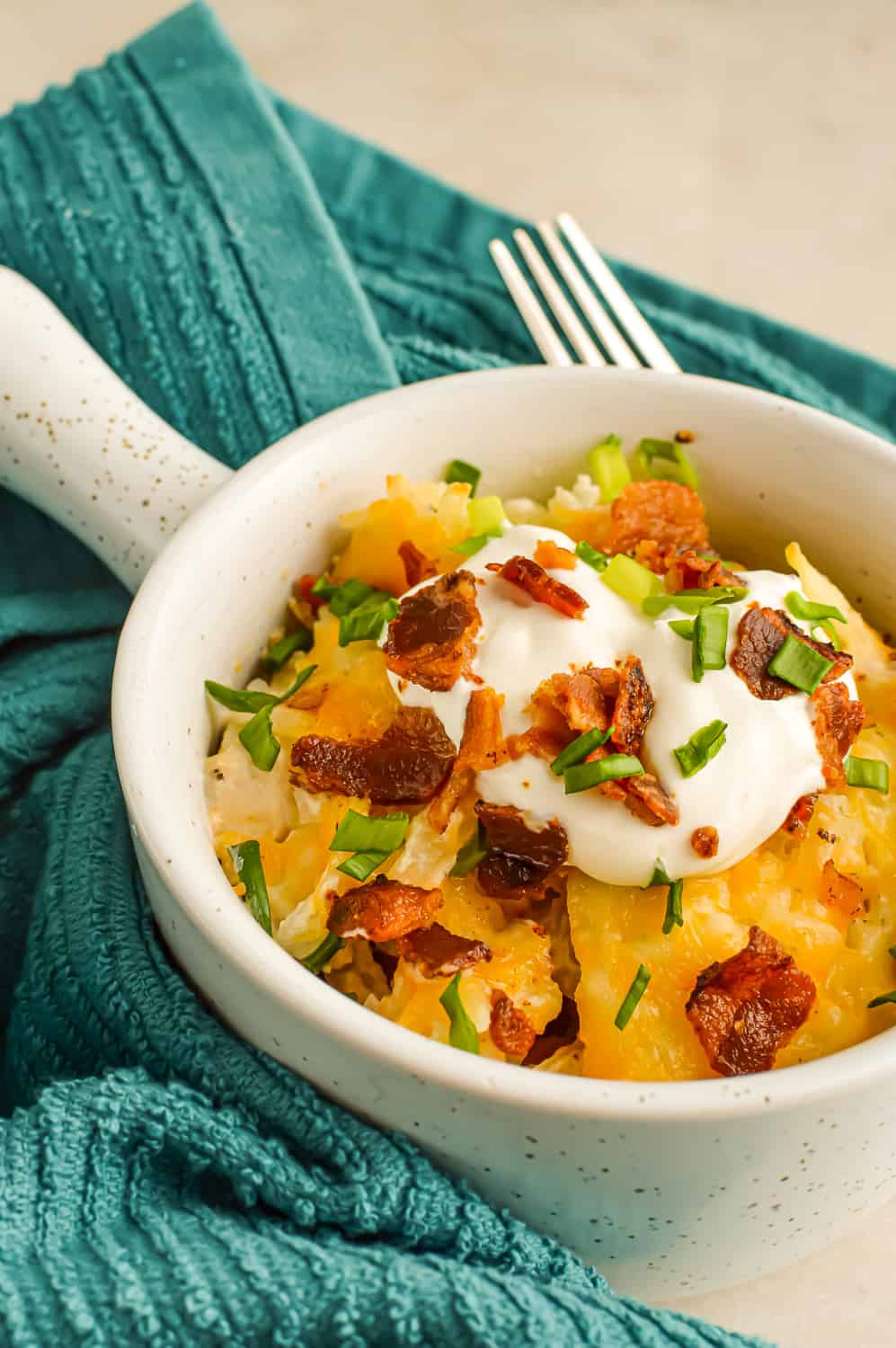 Close up of Chicken Hashbrown Casserole topped with sour cream and bacon.
