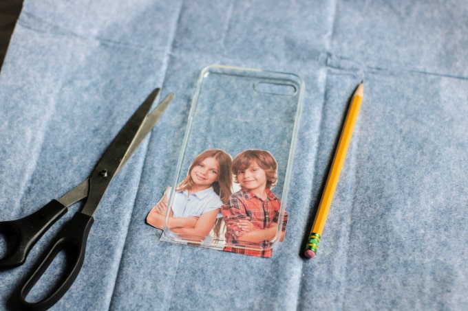 Scissors, phone case, pencil, and photo on a piece of tissue paper.