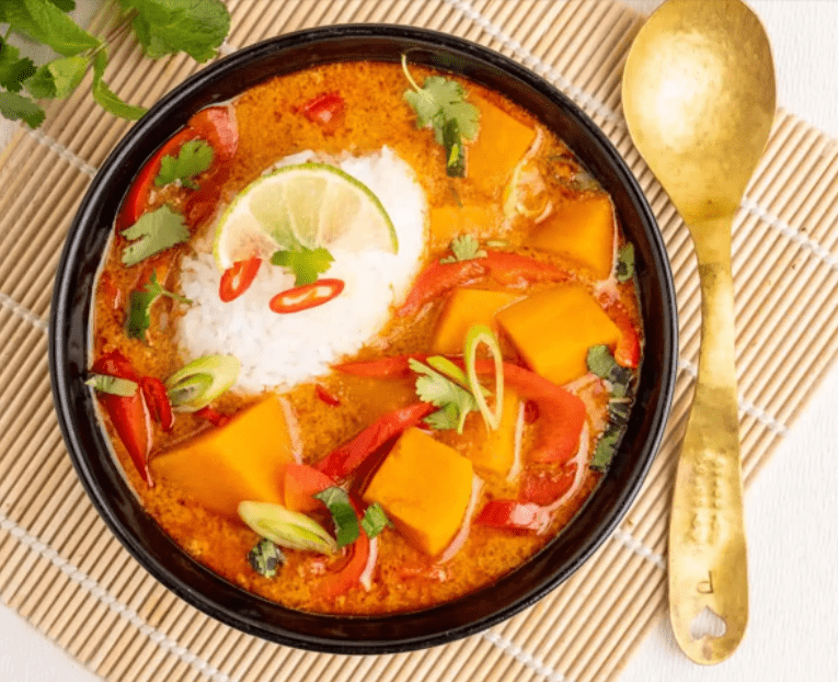 Bowl of Thai Inspired Sweet Potato Curry on a placemat next to a spoon.