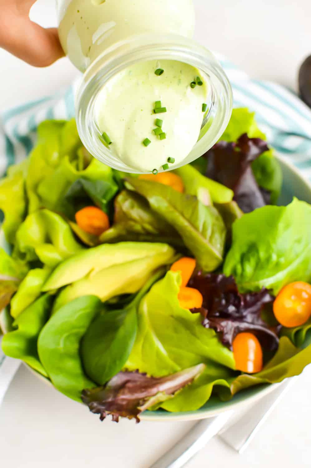 Close up of Avocado Ranch Dressing being poured onto salad.