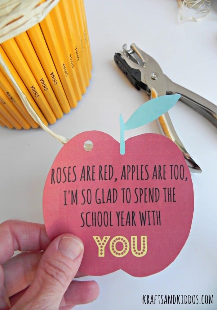 Close up of a hand holding an apple-shaped gift tag.