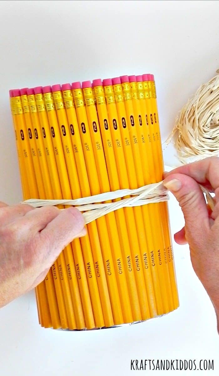 Hands tying rafia around a pencil canister.