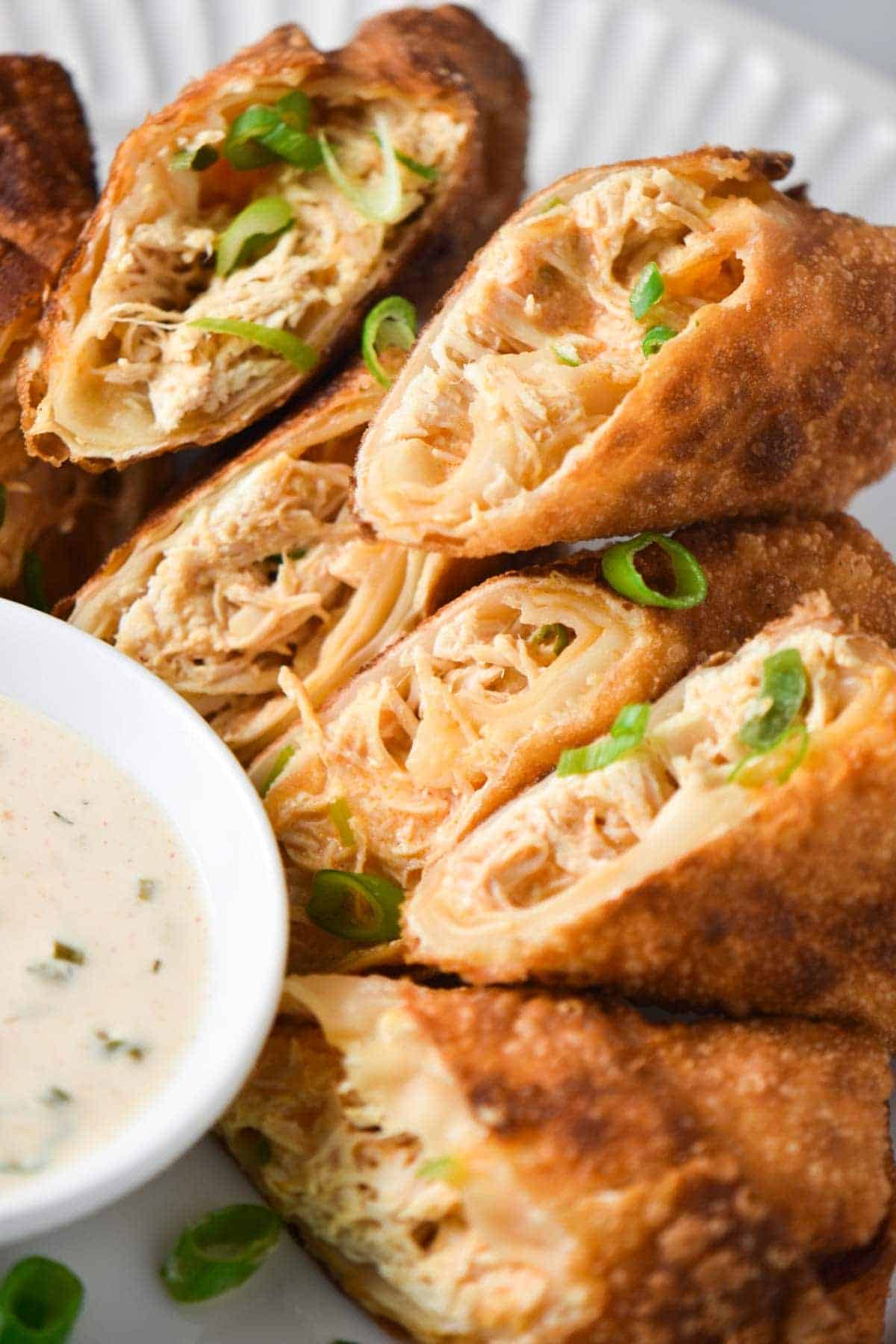 Close up of Buffalo Chicken Eggrolls sliced in half and piled on a plate.