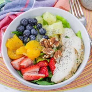 Bowl of Copycat Panera Strawberry Poppyseed Salad with chicken, fruit and nuts.