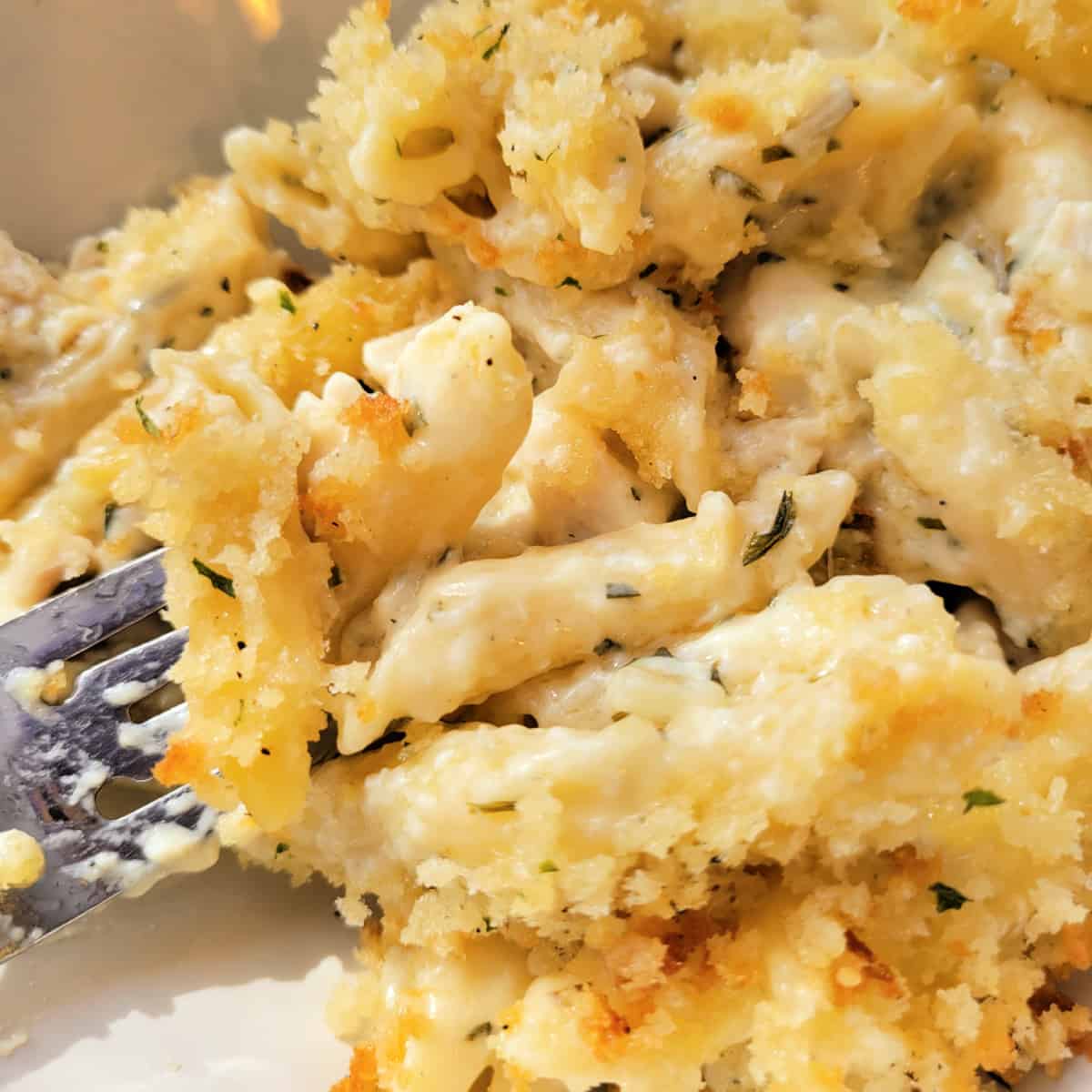 Close up of Creamy Chicken Pasta Bake in a bowl with a fork.