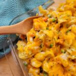 Close up of Creamy Chicken Noodle Casserole in a baking dish with a wooden serving spoon.