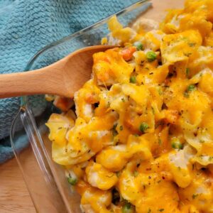 Close up of Creamy Chicken Noodle Casserole in a baking dish with a wooden serving spoon.