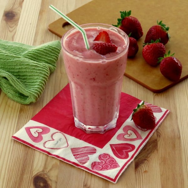 How to Make a Homemade Smoothie + Homemade Smoothie Recipes - Simple Strawberry Smoothie with Yogurt from The Dinner Mom - close up of a strawberry smoothie in a clear glass on a bright pink napkin