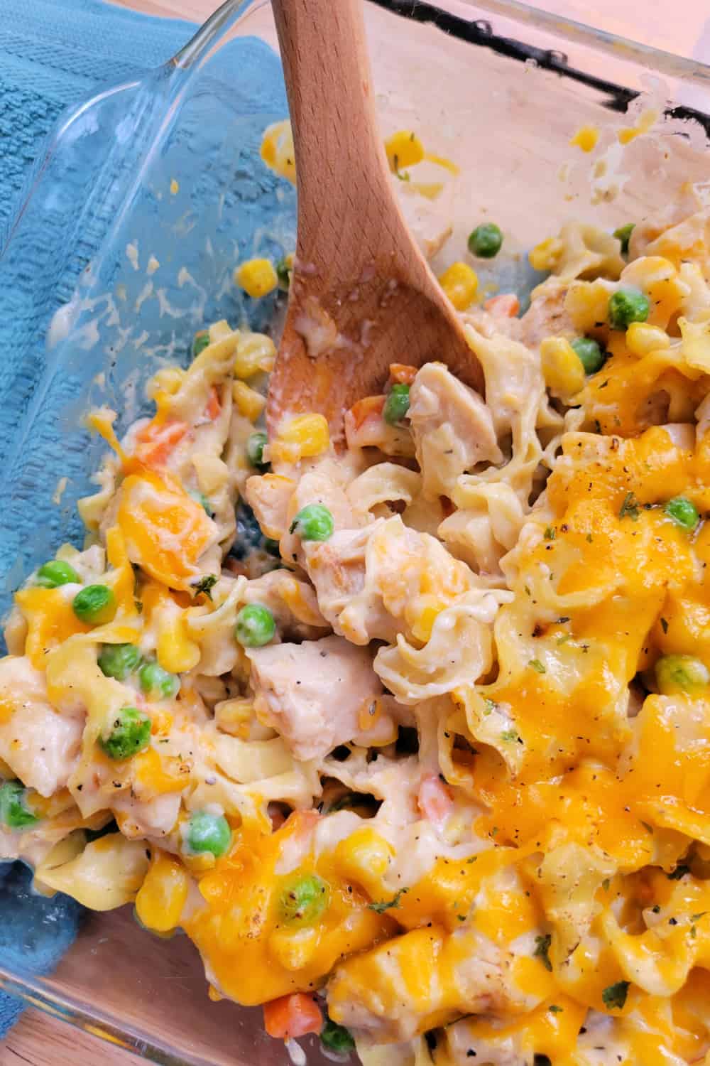 Top down view of Chicken Noodle Casserole Recipe in a baking dish with a wooden spoon.