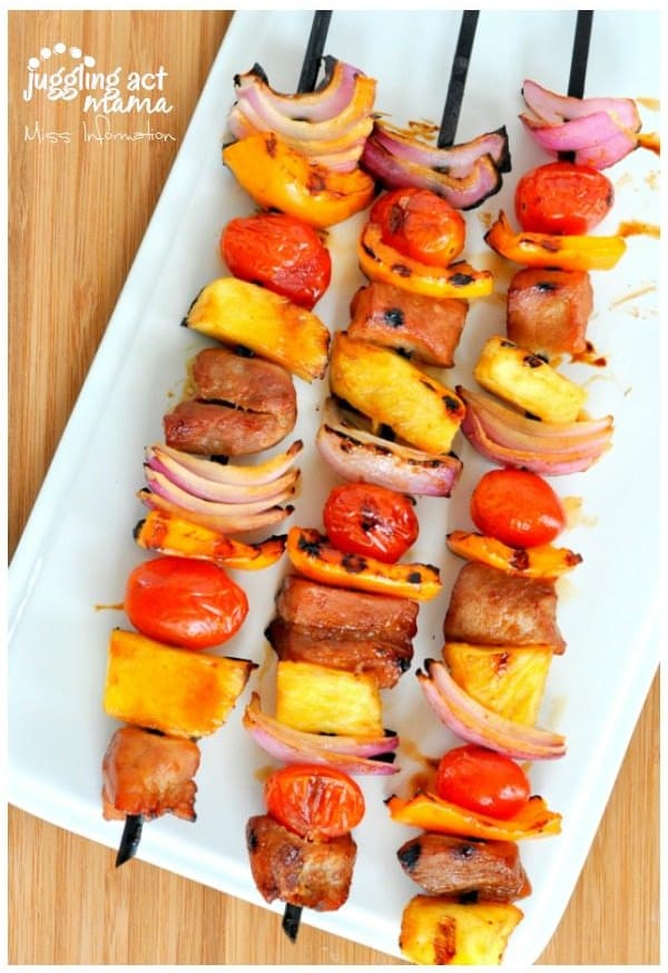 Asian Pork Kabobs with pineapple, peppers, onions, and tomatoes on a white platter.