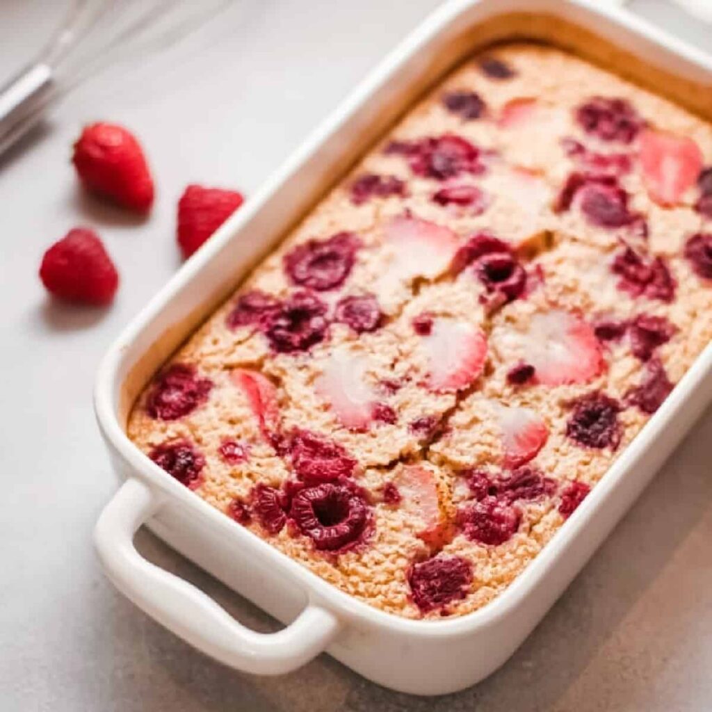 Casserole dish of baked oatmeal with strawberries and raspberries.