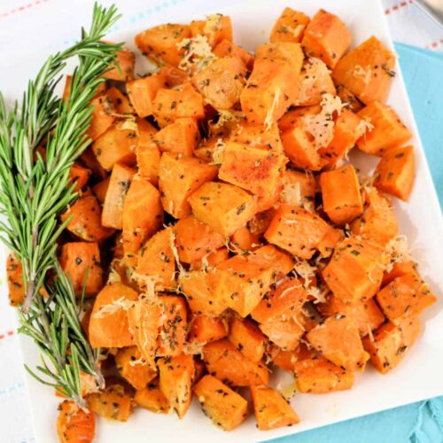 Top down view of Crispy Roasted Sweet Potatoes with fresh rosemary on a white platter.