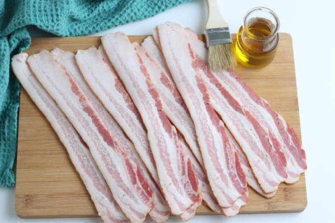 Close up of raw bacon on a cutting board.