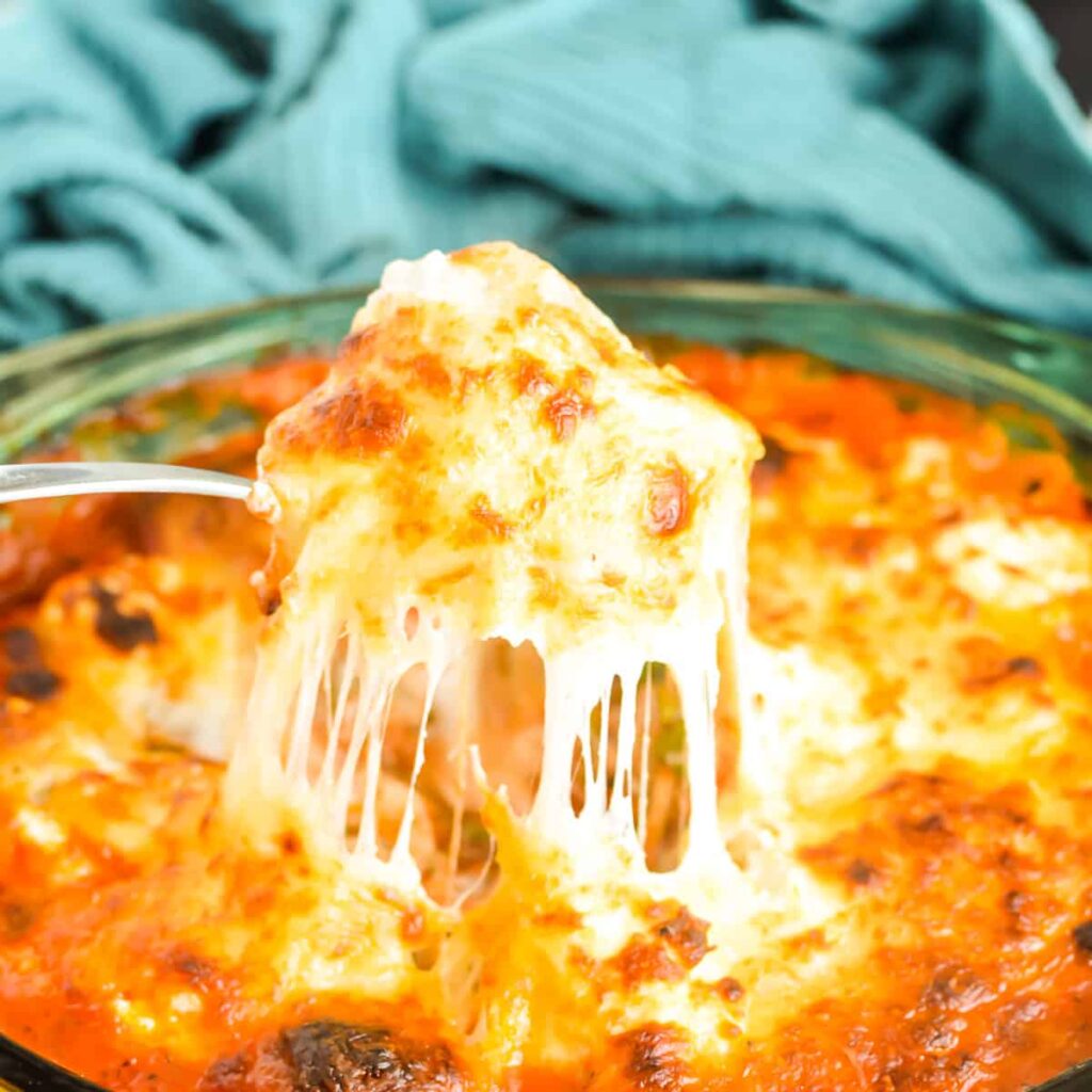 Serving spoon scooping Cheesy Meatball Bake from a casserole dish.