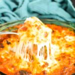 Serving spoon scooping Cheesy Meatball Bake from a casserole dish.