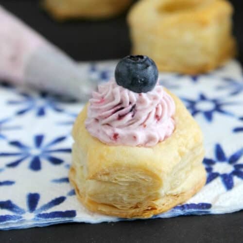 Close up of Blueberry Mousse Puff Pastry Cups on a blue and white napkin.