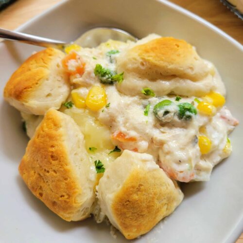 Close up of Chicken Bubble Biscuit Casserole in a bowl with a spoon.