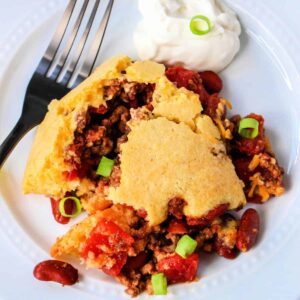 Close up of chili cornbread casserole on a white plate with a fork,