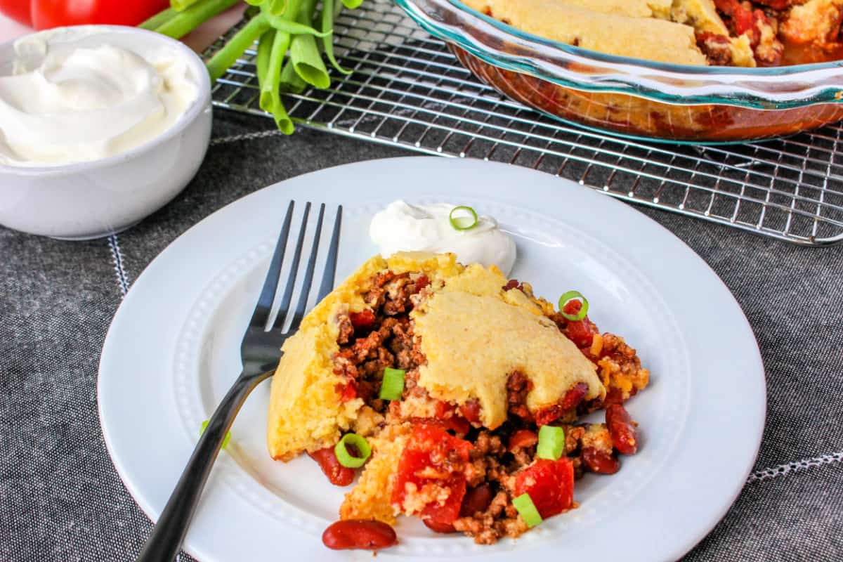 Close up of Jiffy Cornbread Chili Casserole on a white plate with a fork.