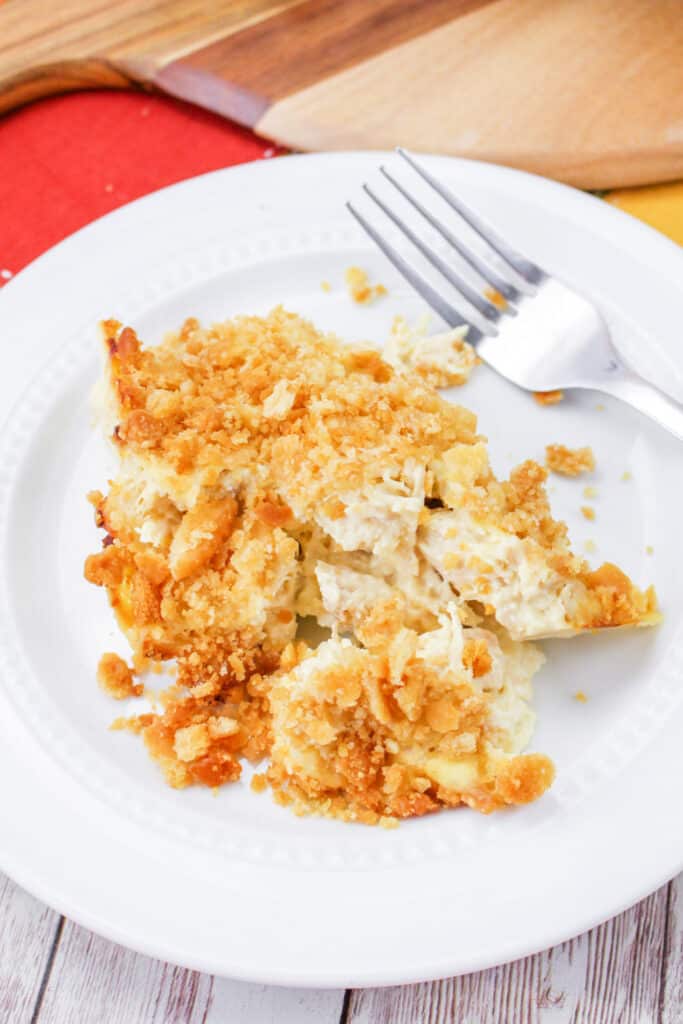 Close up of Million Dollar Chicken Casserole Recipe on a white plate with a fork.