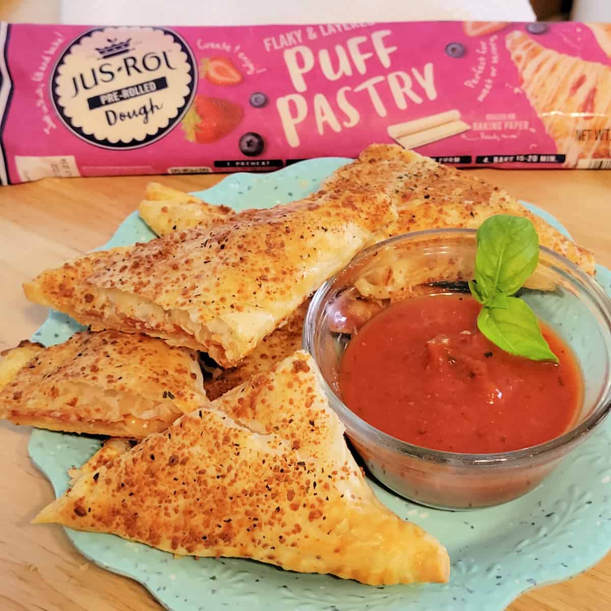 Close up of Puff Pastry Pizza Pockets on a plate with tomato sauce.