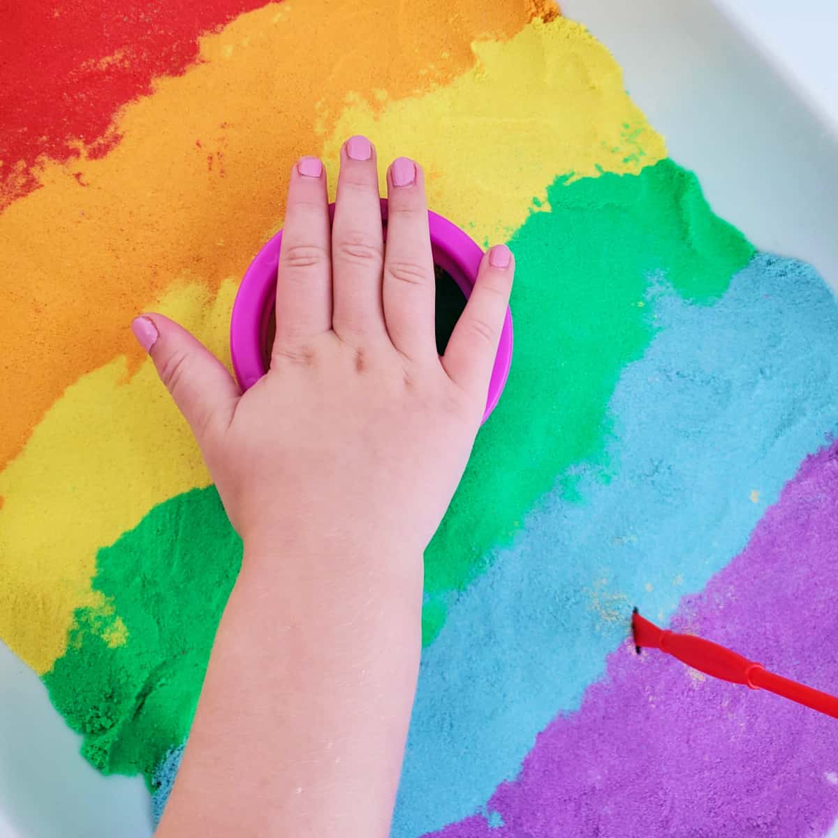 Child's hand playing with homemade kinetic sand.