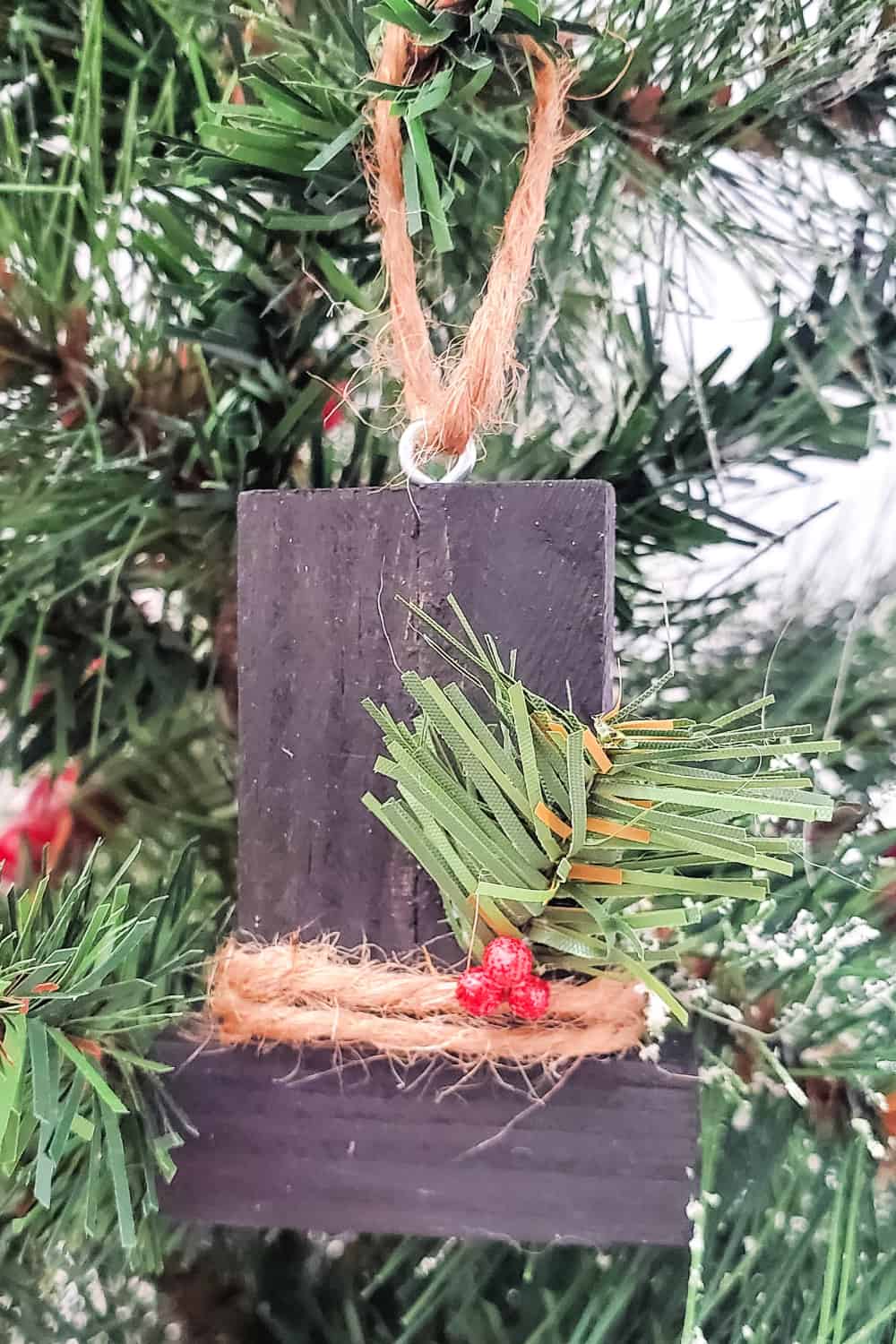 Close up of Snowman Hat Ornament hanging from a Christmas tree.