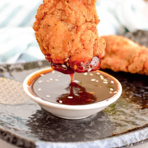Close up of chicken dipped into teriyaki sauce.