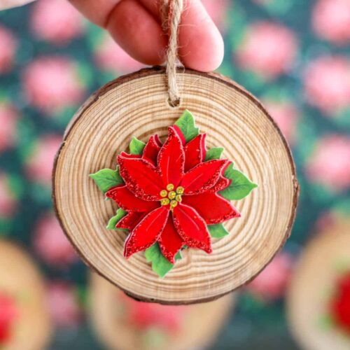 Close up of Hand holding a Wood Slice Poinsettia Ornament.