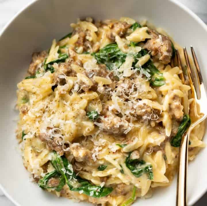 Top down view of Italian Sausage Orzo  in a bowl with a fork.