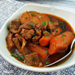 Close up of Beef Bourguignon Slow Cooker in a white bowl with a spoon.