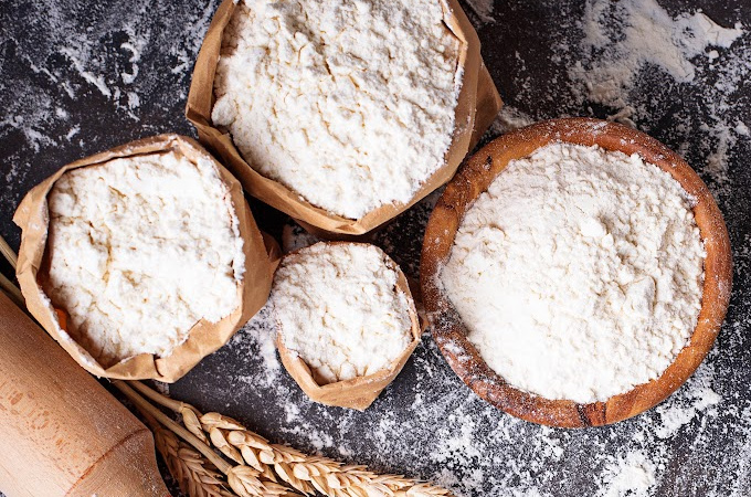 Various types of flour in bags and bowls.