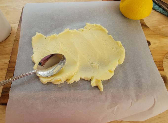Softened butter on parchment paper and a spoon.