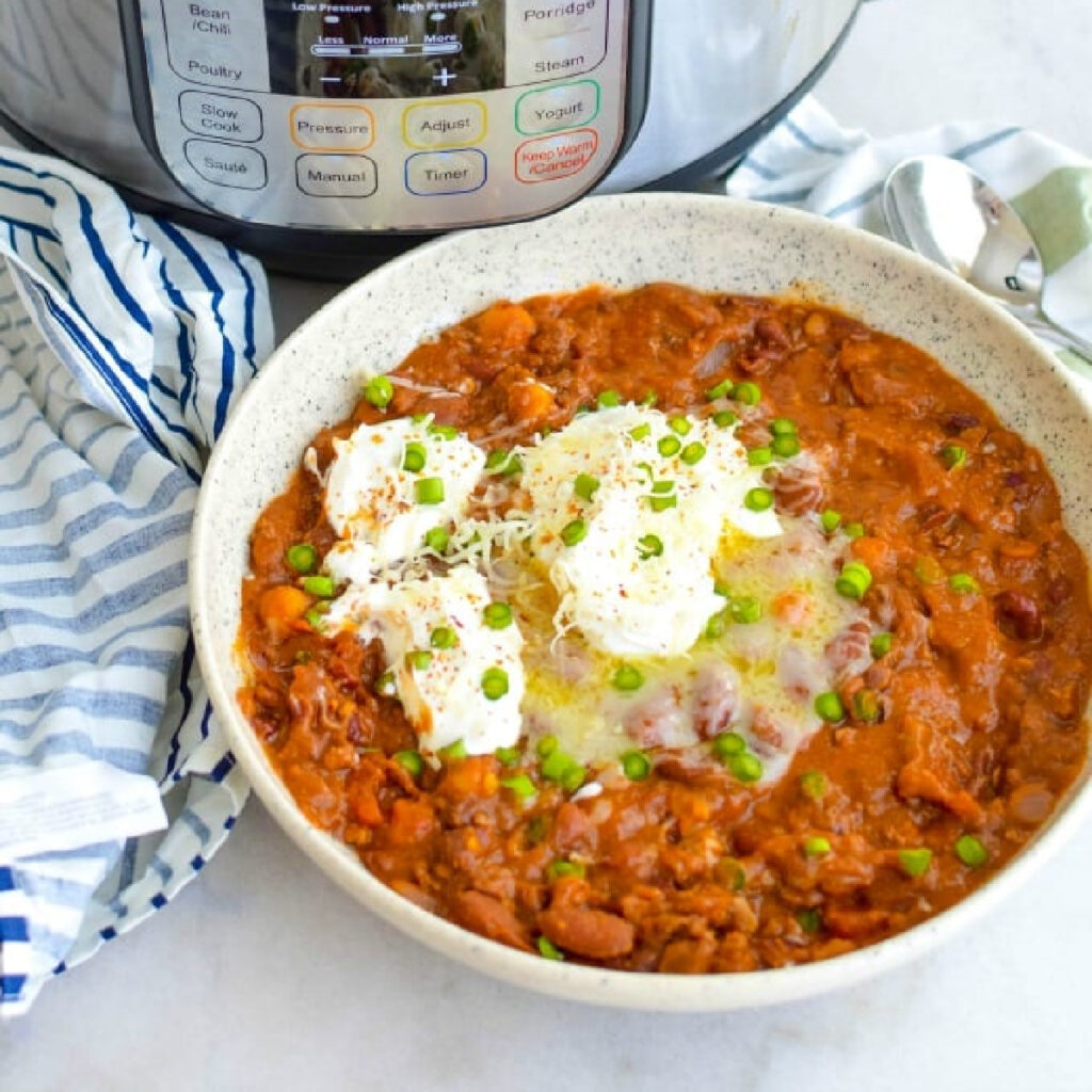 Close up of Instant Pot Beef Chili topped with sour cream and chives.