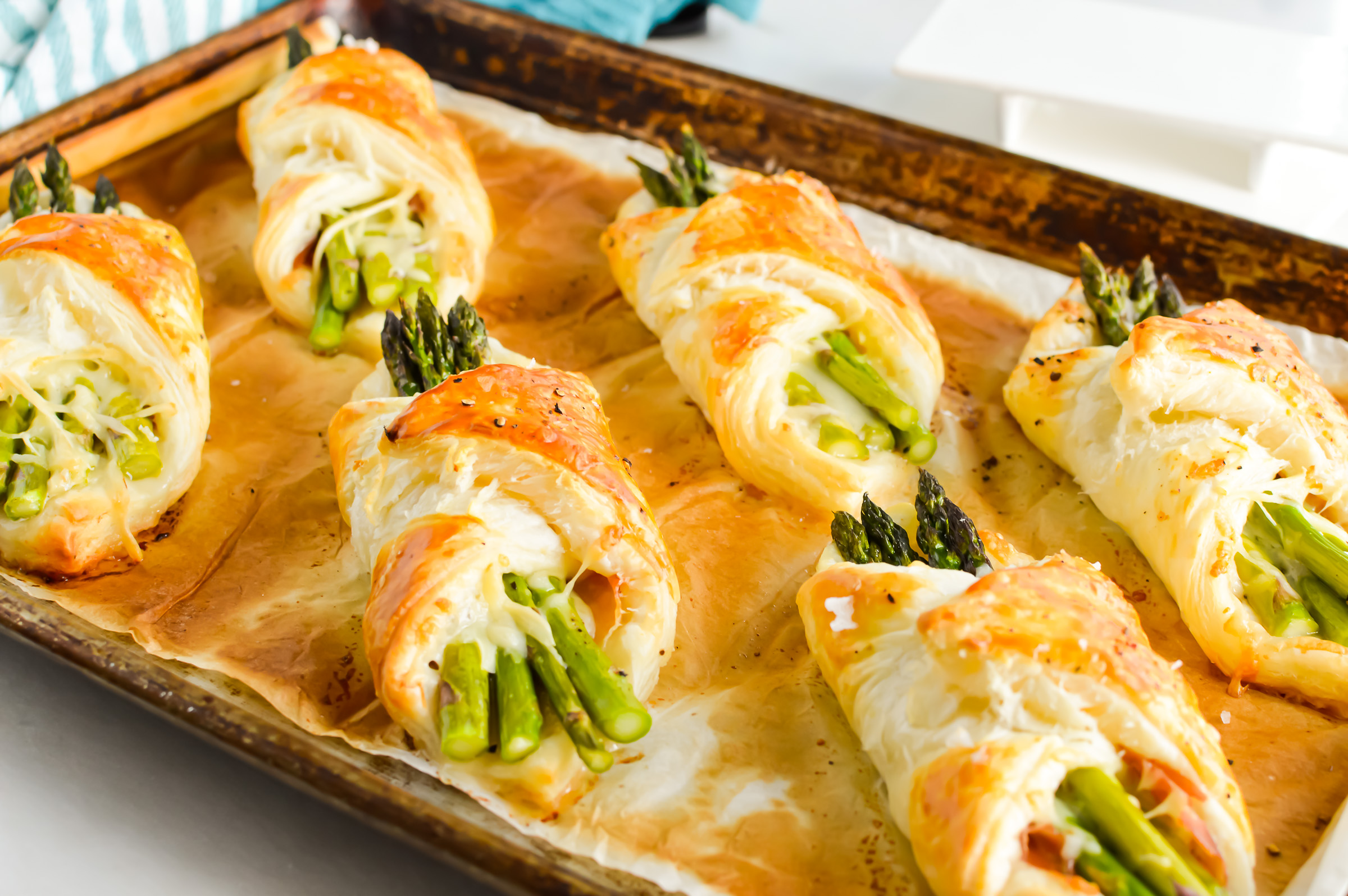 Baked Prosciutto Asparagus Puff Pastry appetizers on a sheet pan.