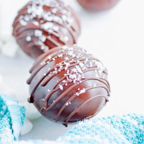 Close up of Salted Caramel Hot Cocoa Bombs drizzled with chocolate and topped with flaked salt.